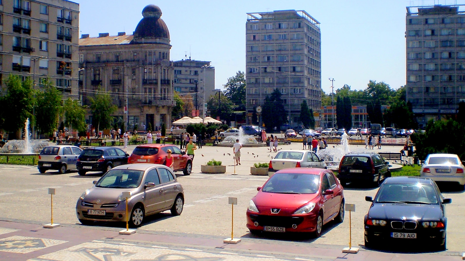 Piață urbană cu manifestație, poliție, cameră de supraveghere și acces la o clădire publică