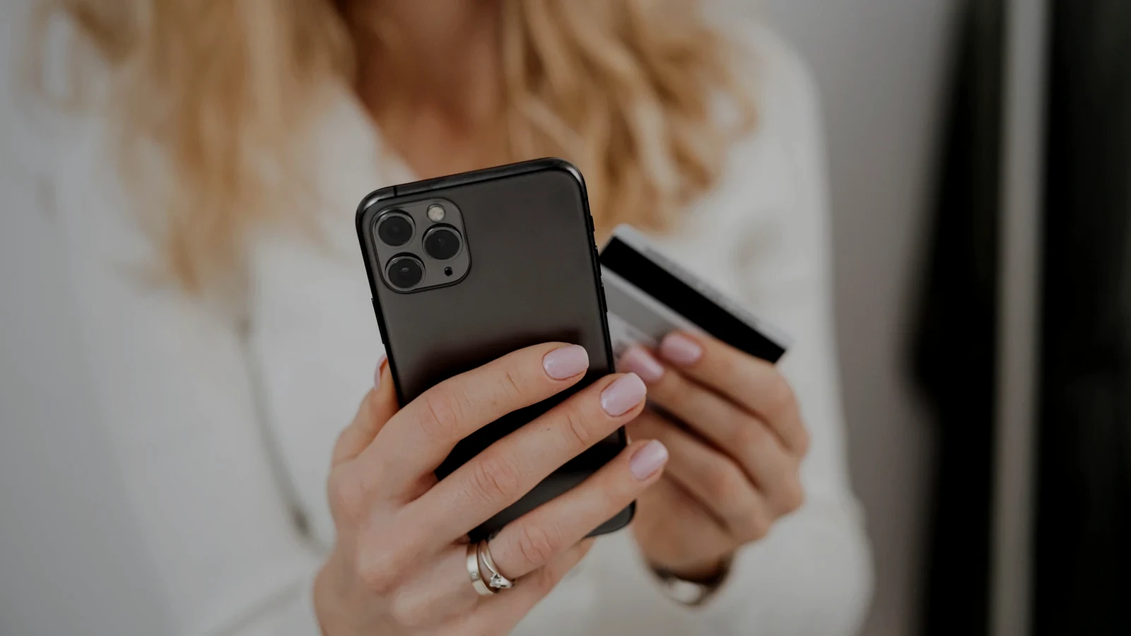 Persoană care ține un telefon și un card bancar