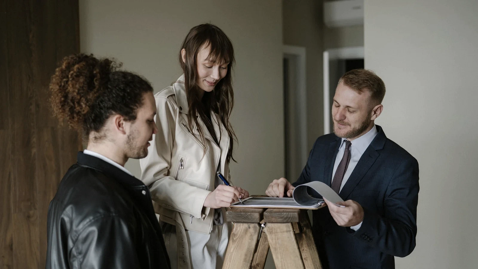 Cumpărători și agent imobiliar analizând documentele unei tranzacții